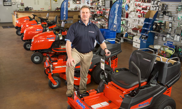 Simplicity dealer posing next to Simplicity zero turn mower