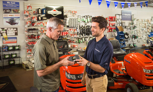 Simplicity dealer showing a lawn mower part to a customer